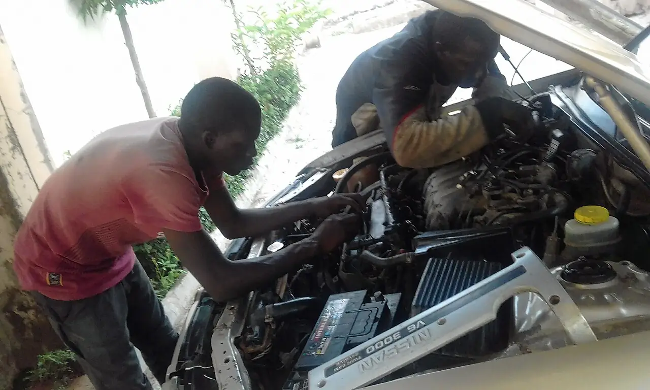 A mechanic working under the bonnet of a car