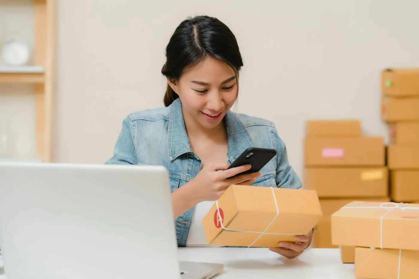 A shop owner checking an online order next to packed boxes